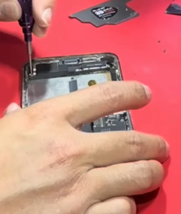 Kỹ thuật viên tháo ốc trong máy khi kiểm tra một iPhone 13 Pro Max không nhận sạc nhanh (khung hình từ video của VNT39)