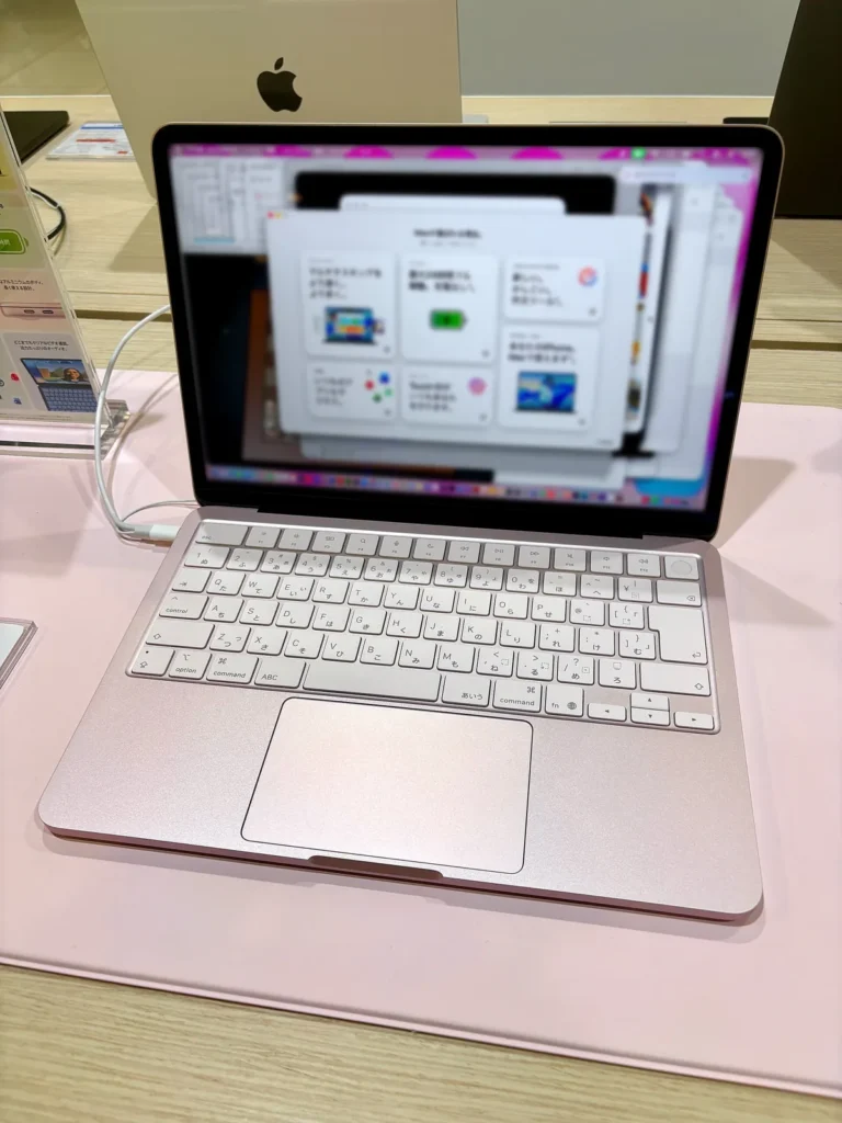 MacBook Neo màu Blush (hồng) mở trên quầy trưng bày của một cửa hàng điện máy ở Nagoya, bàn phím tiếng Nhật