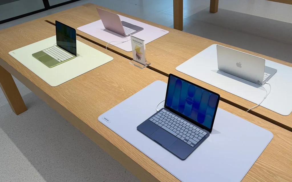 Bàn trưng bày có nhiều chiếc MacBook Neo với các màu Indigo, Citrus, Blush và Silver